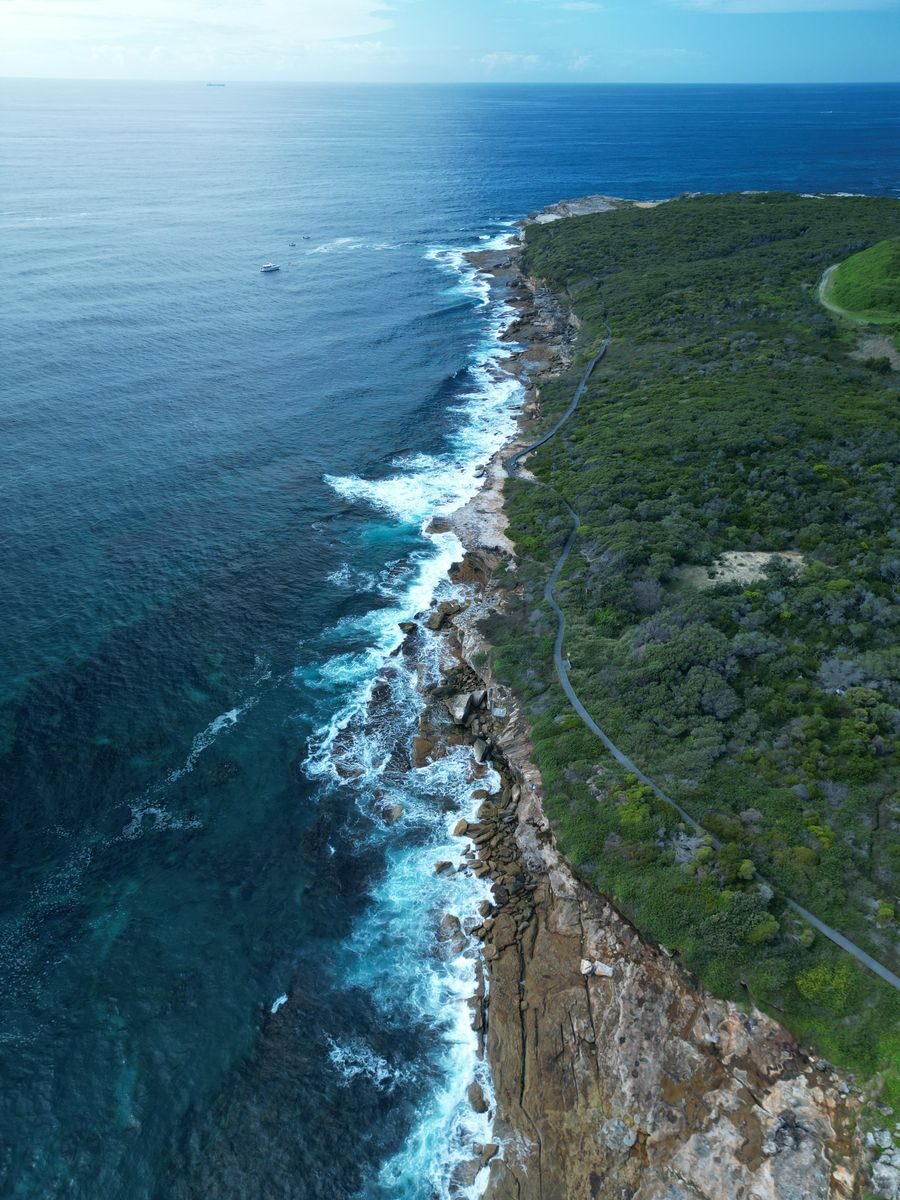 Drone captures the breathtaking natural beauty of a rugged coastline and vibrant ocean waves.