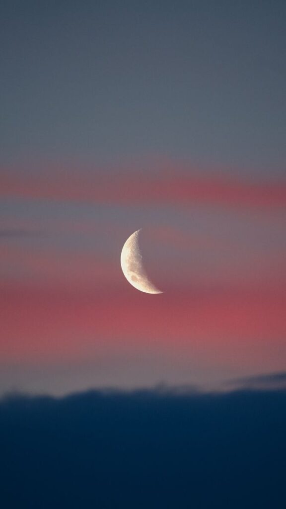A serene crescent moon set against a vivid pink and blue twilight sky, creating a peaceful atmosphere.